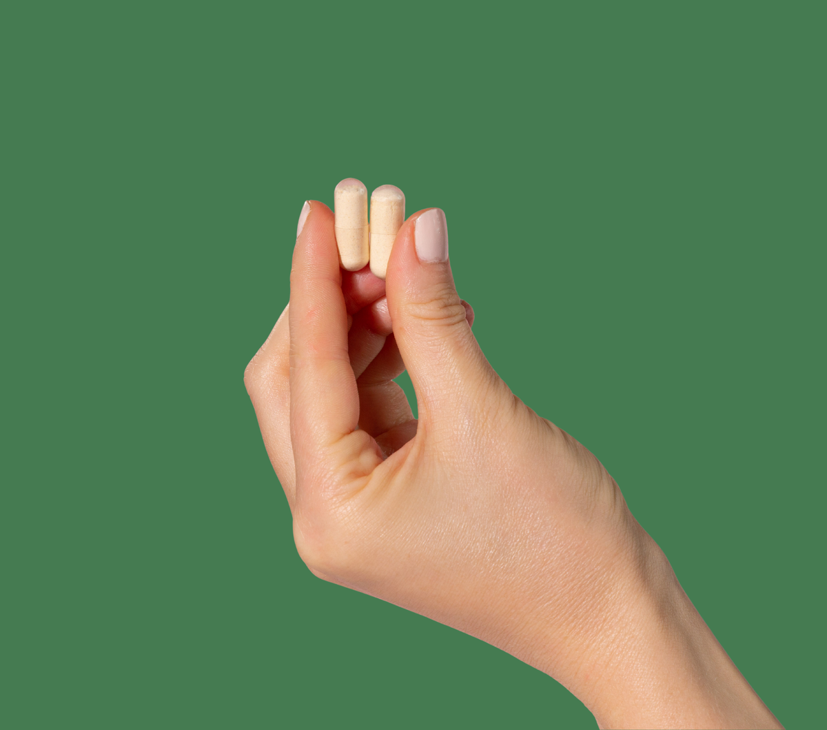 Hand holding two NaturoElite pullulan capsules